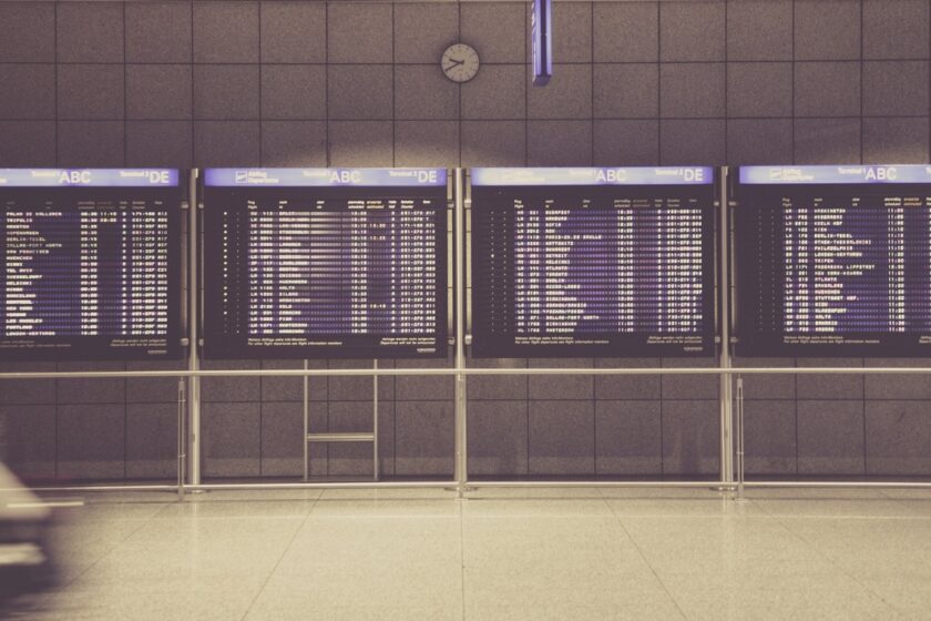 l’immagine rappresenta la sala di attesa di un aeroporto, con i tabelloni degli orari dei voli 