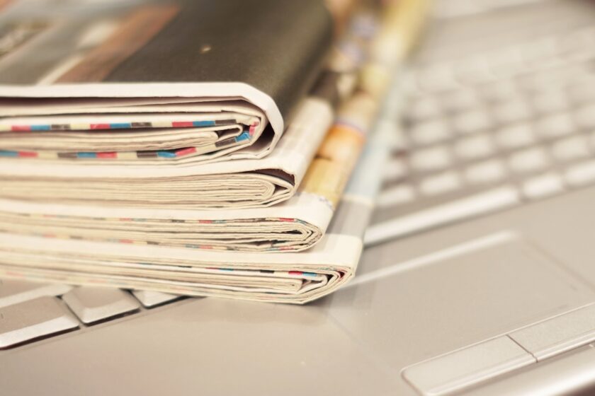 l’immagine rappresenta un personal computer e dei giornali 
