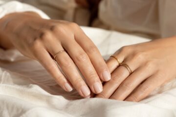 Unghie curate con manicure nude lattiginosa e mani eleganti con anelli sottili.